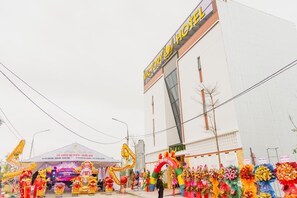 Un hôtel avec une enseigne bien visible, un espace couvert agrémenté de décorations et une variété de compositions florales colorées à l’avant.
