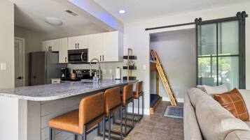 A modern kitchen with a bar area, a staircase, and a living area with a sofa.