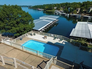 Une piscine dotée d’une terrasse, entourée d’une zone de quai avec des bateaux, le tout se fondant dans un paysage arboré et aquatique.