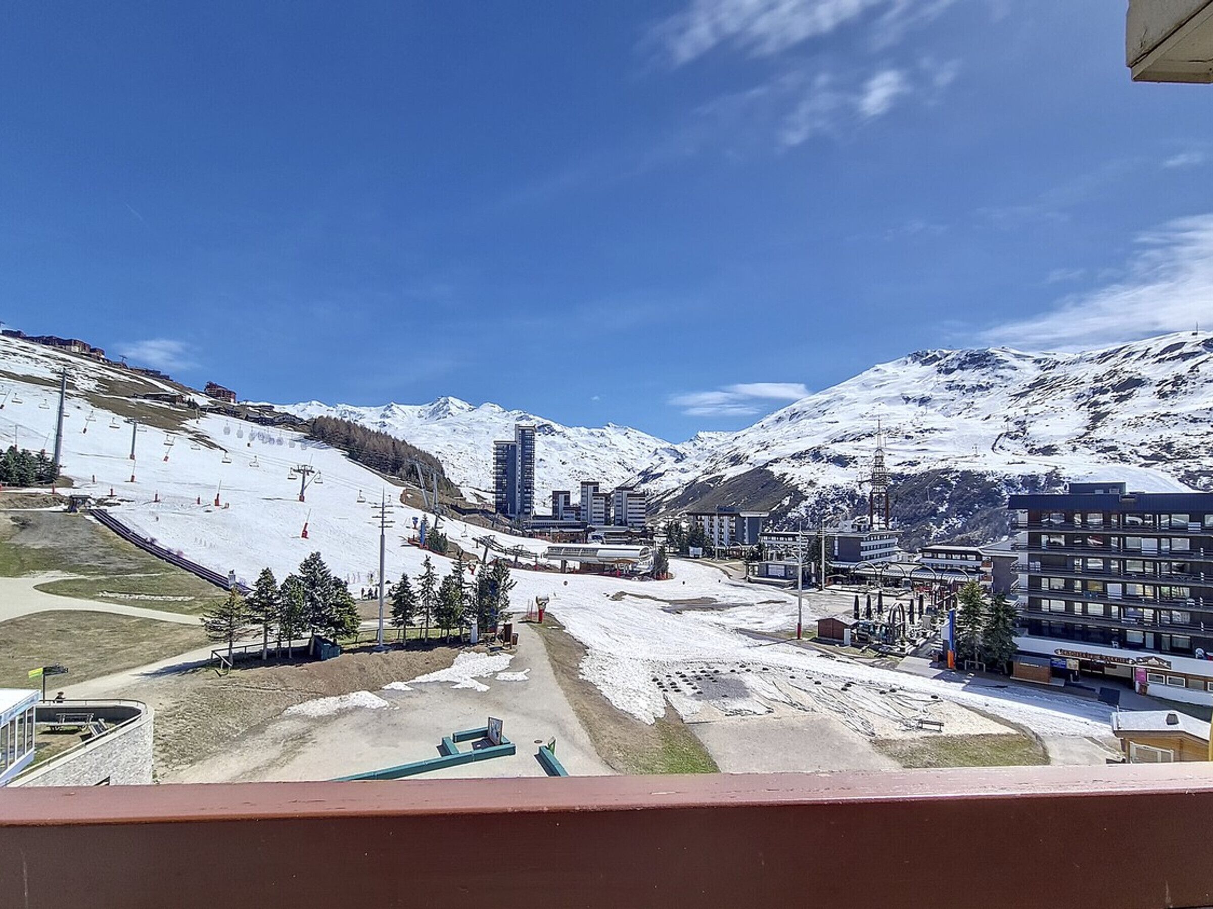 A snow-covered mountain landscape with a ski resort, buildings, and a clear sky.