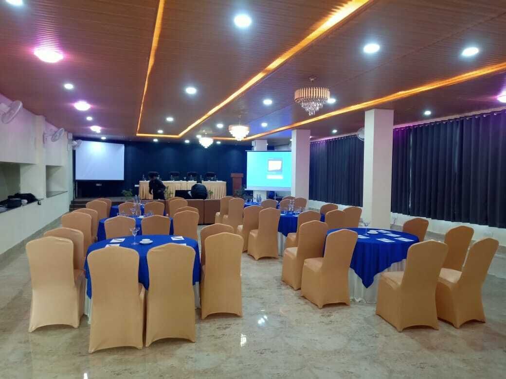 A conference room with round tables, chairs, and a projection screen.