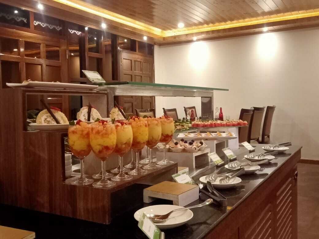 Un área de bufé con diferentes opciones de comida y una barra con platos y cubiertos.
