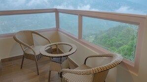 Un balcón con mobiliario de mimbre y vistas a un paisaje montañoso.
