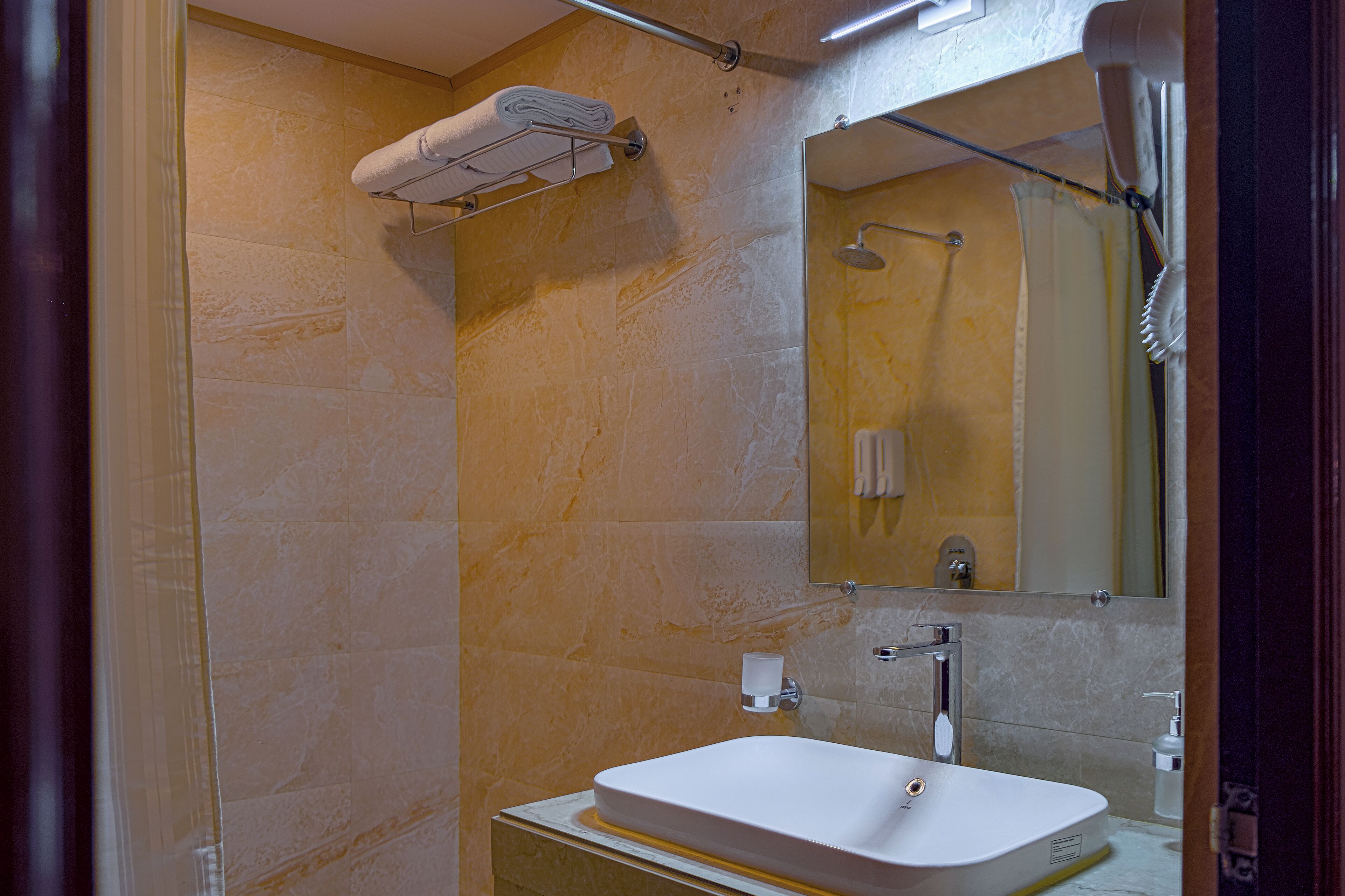 A modern bathroom with a built-in sink, a towel rack, a mirror, and a shower area.