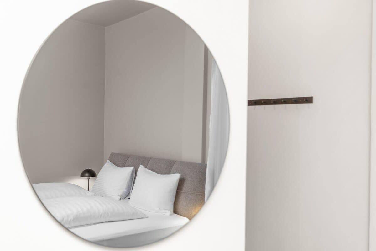 Un dormitorio con cama, almohadas, una mesita de noche y una lámpara.