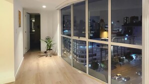 Ein modernes Interieur mit einem großen Schiebeglastür, die auf einen Balkon führt, einem Holzboden und einem Blumentopf.