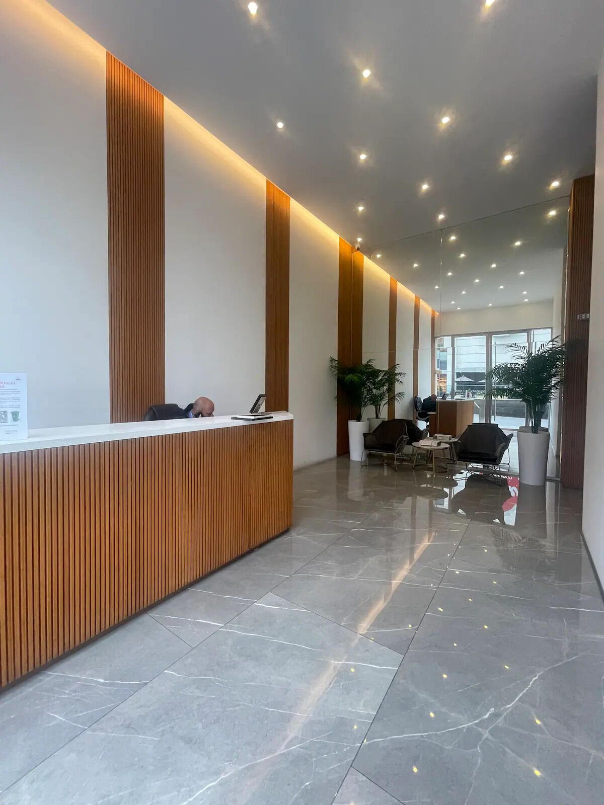 A modern reception area with a wooden reception desk, seating area, and large windows.