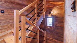 Eine Holztreppe mit Handlauf und einem kleinen Fenster oben.