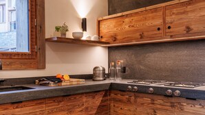 Eine moderne Küche mit Holzschränken, einem Gasherd und einer Arbeitsplatte mit Wasserkocher und Glasflaschen.