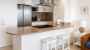 A modern kitchen with a granite countertop, stainless steel appliances, and white cabinetry.