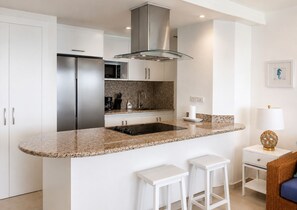 A modern kitchen with a granite countertop, stainless steel appliances, and white cabinetry. - Best View 8th Floor| Beachfront| Fast Wifi| Pool (Juan Dolio)