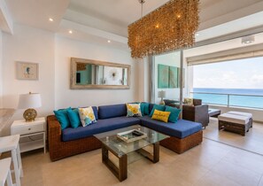 Una sala de estar moderna con un sofá modular, una mesa de centro de vidrio y vistas al océano.