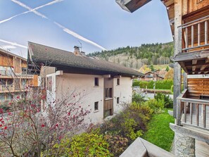 Ein modernes Chalet mit geneigtem Dach, einem Steinfundament und Blick auf einen bewaldeten Hang.