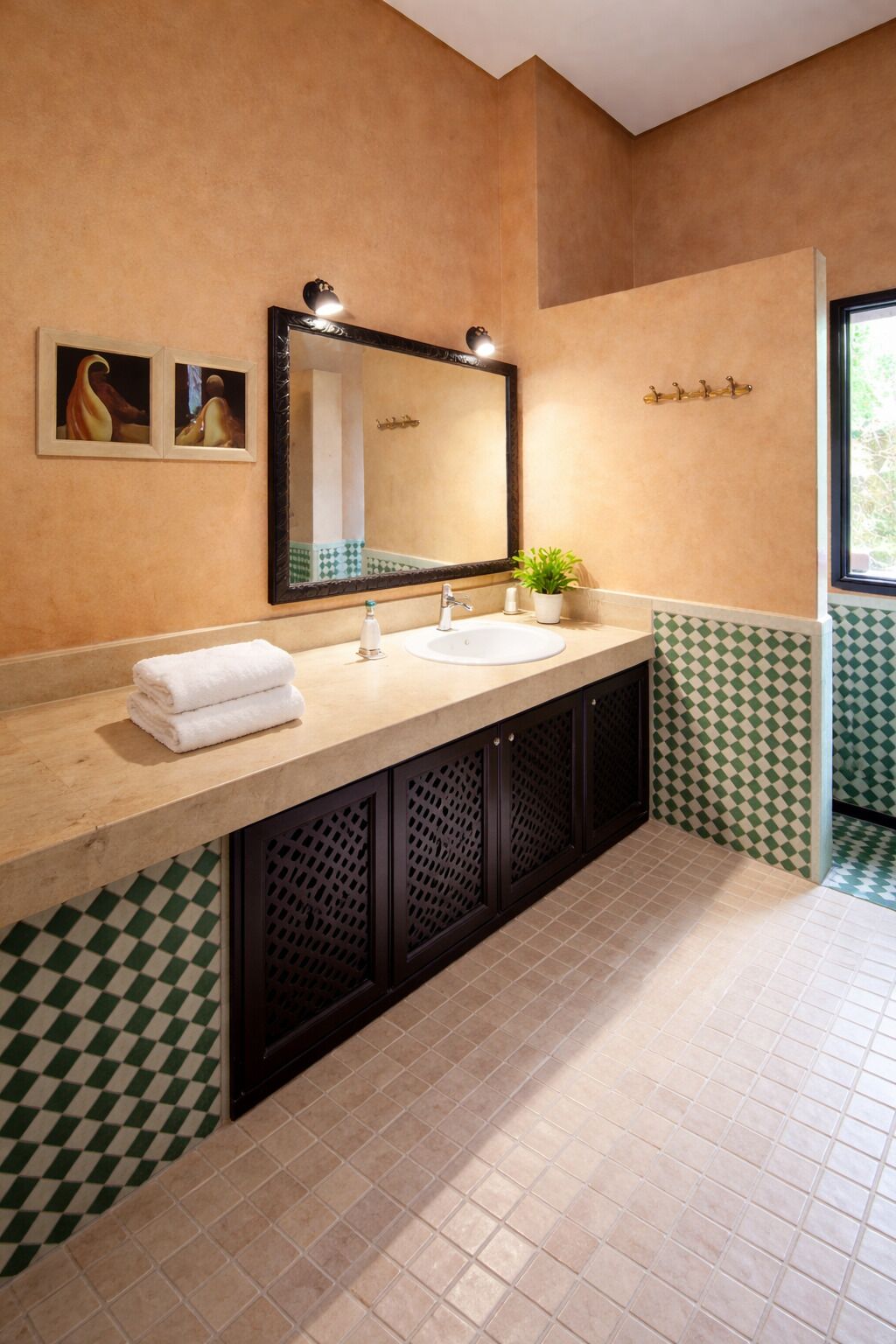 Une salle de bain avec un grand miroir, deux lavabos, un porte-serviettes et une plante en pot.