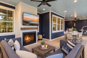 A cozy outdoor living area with a fireplace, comfortable seating, and a dining setup.
