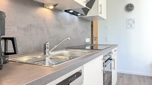 Una cocina moderna con un lavamanos de acero inoxidable, una campana extractora empotrada y un lavavajillas compacto.