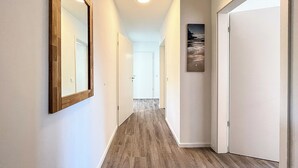 Un pasillo con suelo de madera, paredes blancas y un cuadro enmarcado en la pared.