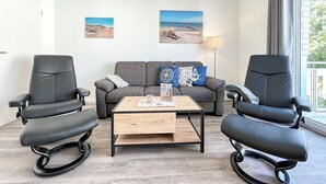 Una sala de estar moderna con un sofá, dos sillones, una mesa de centro y dos cuadros colgados en la pared.