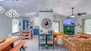 A spacious living room with a wooden dining table, a sofa, a TV, and a fireplace. - Game Room-Dogs-Fence yrd- King Bed (Tallahassee)