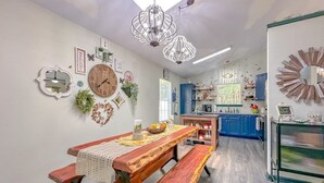 A dining area with a wooden table and benches, a kitchen in the background, and decorative wall art. - Game Room-Dogs-Fence yrd- King Bed (Tallahassee)