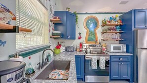 A kitchen with blue cabinets, a microwave, a stove, and a sink. - Game Room-Dogs-Fence yrd- King Bed (Tallahassee)