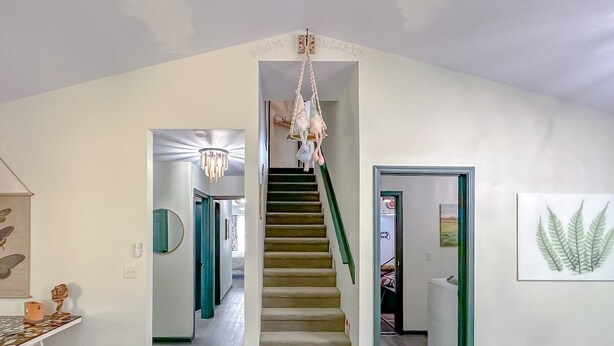 A spacious hallway with a staircase, a chandelier, and a framed artwork on the wall. - Game Room-Dogs-Fence yrd- King Bed (Tallahassee)