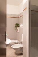 Baño con dos inodoros, un lavabo y zona de ducha.