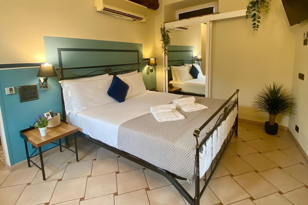 Un dormitorio con cama, mesitas de noche, un espejo y una planta en maceta.