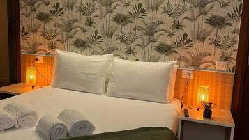 Una habitación de hotel con una cama, dos mesitas de noche y una pared decorada con un estampado floral.