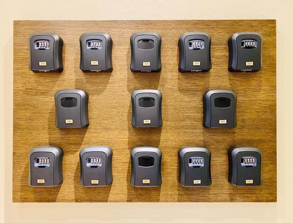 A wooden panel with 15 door locks, each labeled with a unique number from 101 to 115.