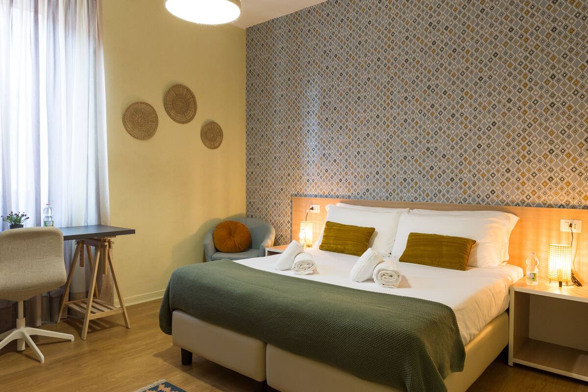 Habitación de hotel ordenada con cama, escritorio y silla.