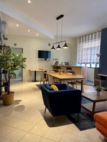 Ein moderner, hell erleuchteter Raum mit Essbereich, einer Couch und einem an der Wand befestigten Fernseher.