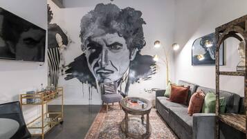 A modern living room with a large abstract mural, a grey sofa, a coffee table, and a patterned rug.