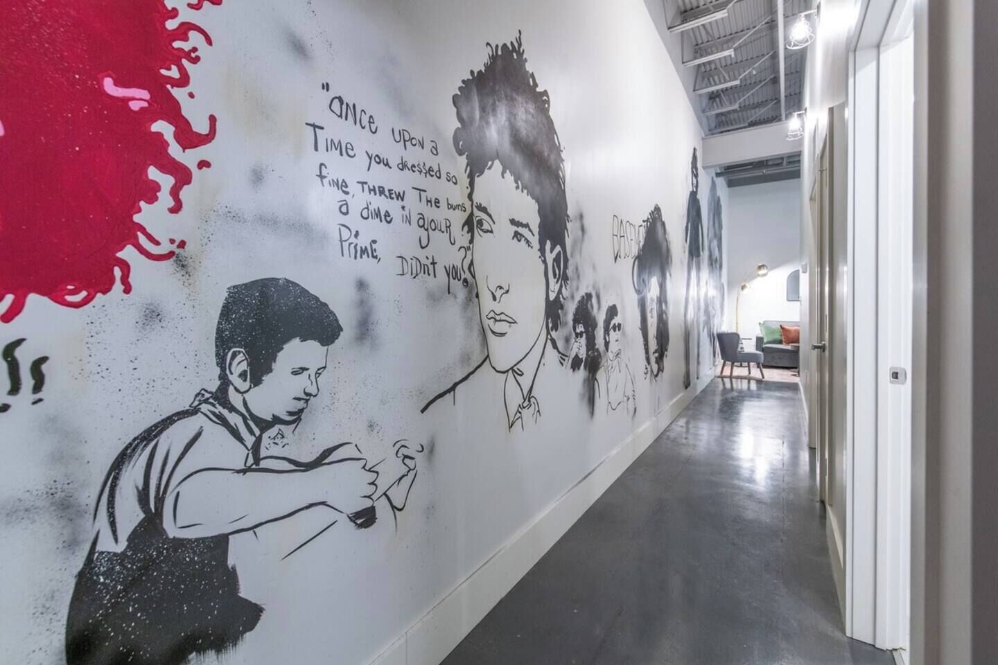A hallway with graffiti art on the walls and a red splash on the left.