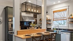 A modern kitchen with a central island, stainless steel appliances, and a hanging light fixture.