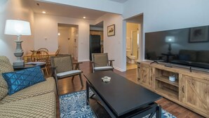 A modern living room with a sofa, dining table, chairs, a TV, and a kitchen area visible in the background. - This townhouse is a 4 bedroom(s), 3 bathrooms, located in Lexington, KY. (Lexington)