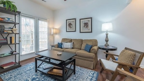 A living room with a sofa, coffee table, bookshelf, and two wall-mounted lamps. - This townhouse is a 4 bedroom(s), 3 bathrooms, located in Lexington, KY. (Lexington)