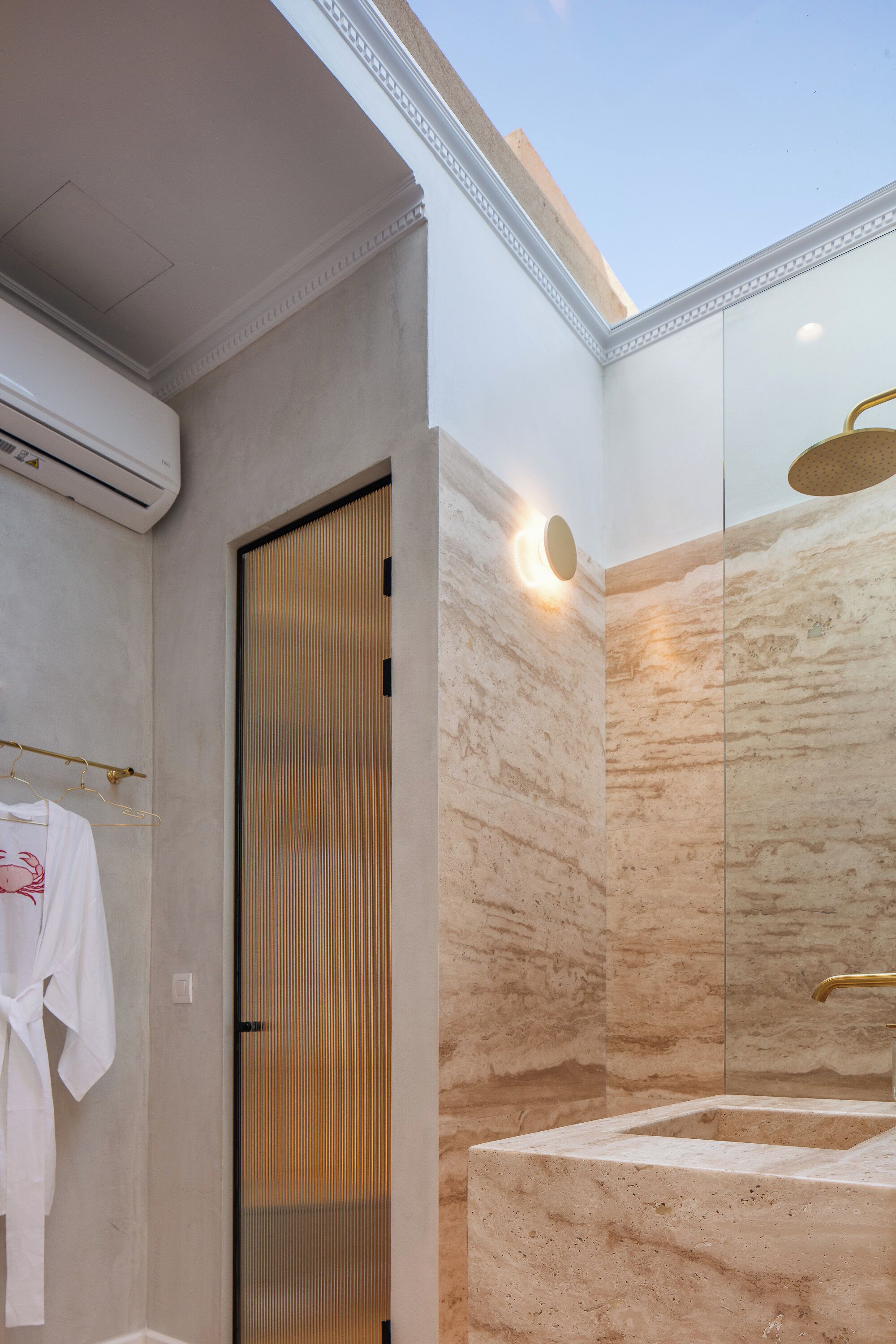 A modern bathroom with a large mirror, a towel rack with a white towel, and a shower area with a gold showerhead.