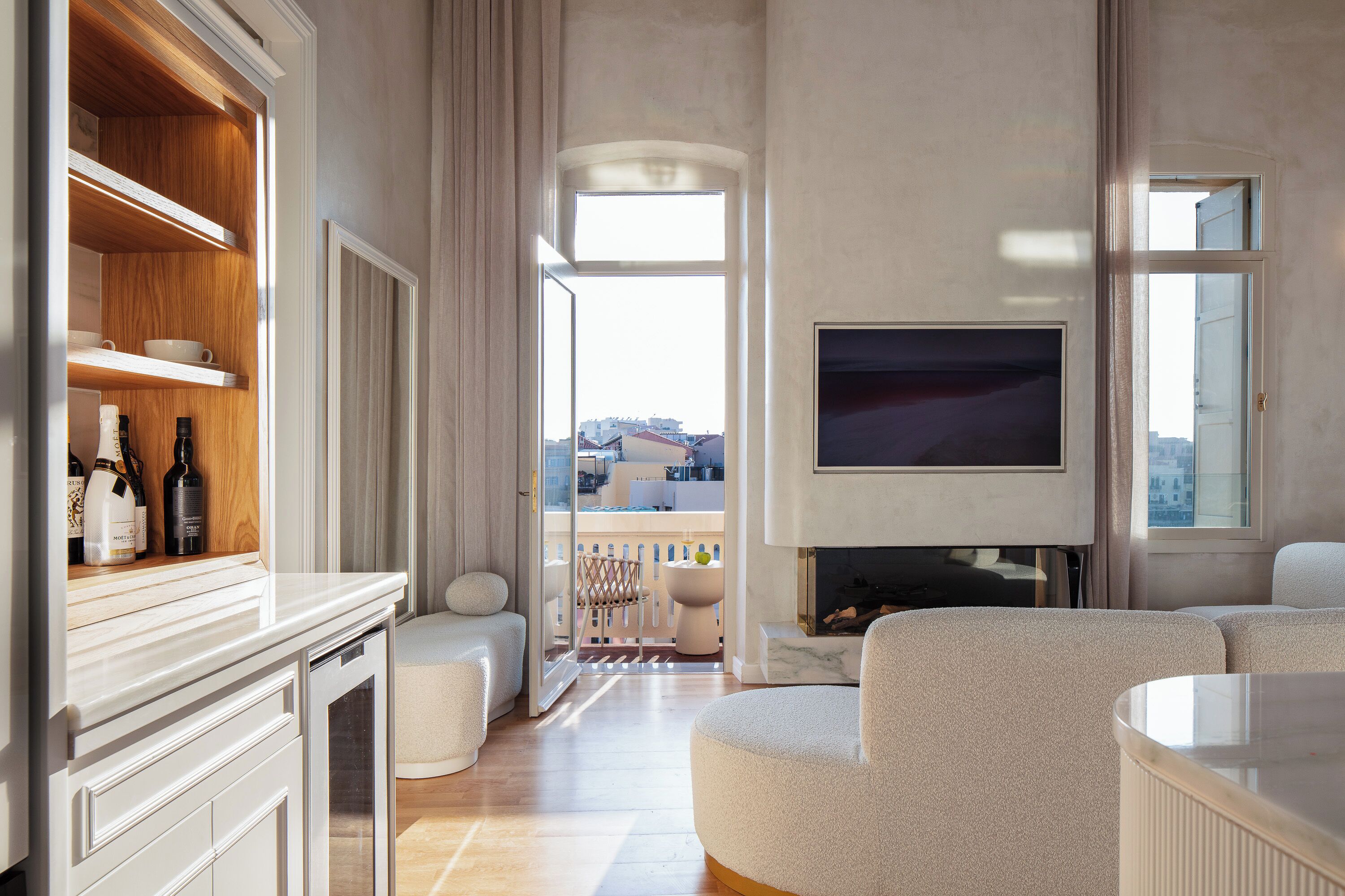 A modern living room with a fireplace, a television, and a balcony with a view of the city.
