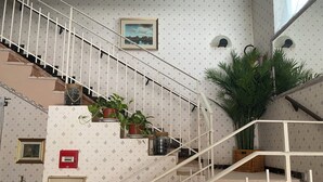 A staircase with white railings, potted plants, and framed pictures on the walls. - Viale Lazzaro Papi (Rimini)