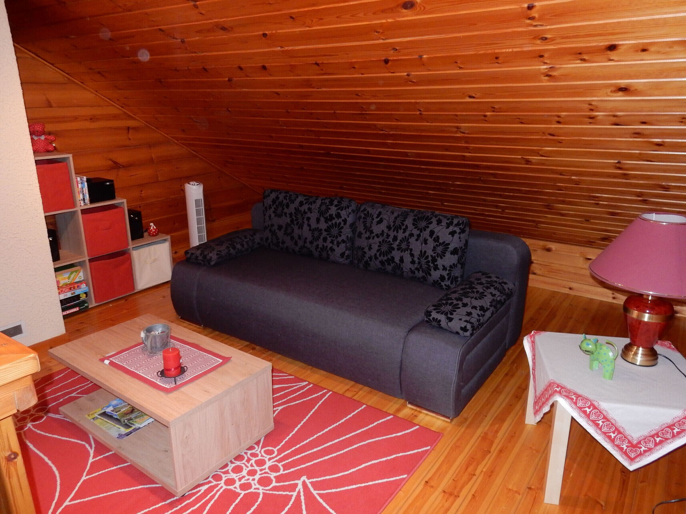 Une pièce confortable avec un canapé, une petite table, une lampe et une bibliothèque.