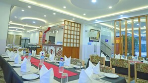 A conference room with round tables, white tablecloths, and water bottles. - The BD Hotel (Thimphu)