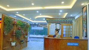 A reception area with a wooden desk, a sign reading "RECEPTION," and a wall decorated with potted plants. - The BD Hotel (Thimphu)