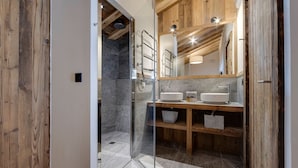 A modern bathroom with a glass shower enclosure, wooden accents, and a large mirror above the sink.