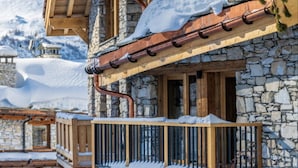 A stone building with a wooden balcony and snow-covered surroundings.