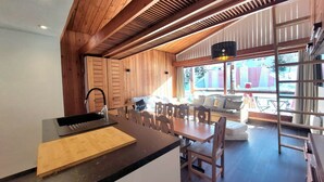 A modern kitchen with wooden beams, a large island, and a dining area with a view of the outside. - Spacious Apartment 9 pers. · Ski-in/Ski-out · Wifi included (Les Arcs 1800)