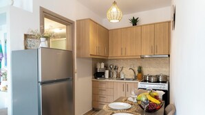Eine kompakte Küche mit Holzschränken, einem Edelstahlkühlschrank und einer Essecke mit Tisch für zwei Personen.