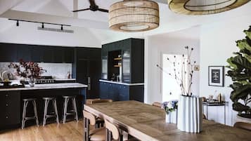 A modern kitchen with dark cabinets, a wooden dining table, and bar stools.