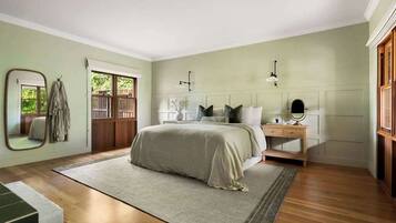A bedroom with a bed, bedside table, mirror, and a view of the outside.