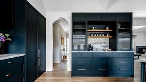 A modern kitchen with dark cabinetry, a marble countertop, and built-in shelves.